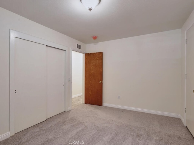 unfurnished bedroom featuring light carpet and a closet