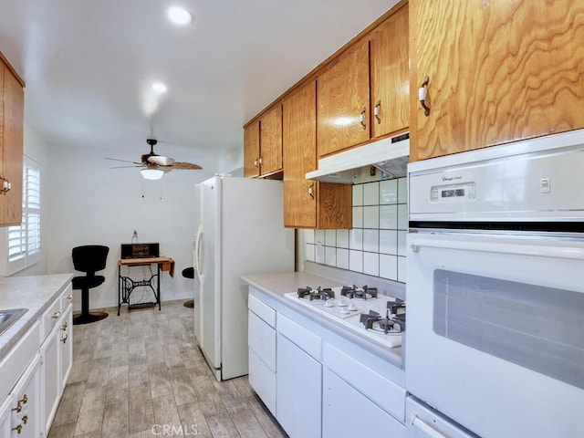 kitchen featuring white appliances, white cabinets, ceiling fan, light wood-type flooring, and tasteful backsplash