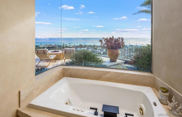 bathroom with a tub to relax in, plenty of natural light, and a water view