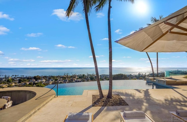 view of pool featuring a hot tub, a water view, and a patio area