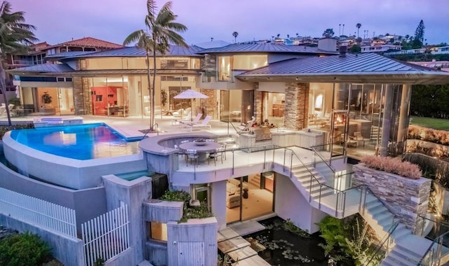 pool at dusk featuring a patio area and an in ground hot tub