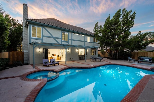 pool at dusk with an outdoor hangout area, a patio, and an in ground hot tub