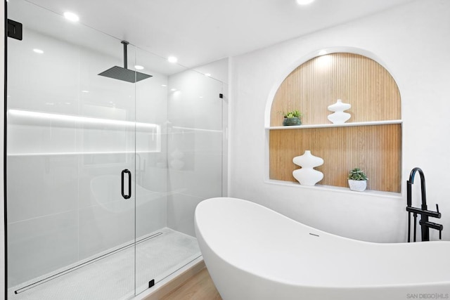 bathroom featuring hardwood / wood-style floors and plus walk in shower