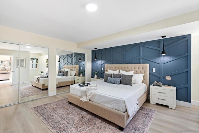 bedroom with light hardwood / wood-style flooring and multiple closets