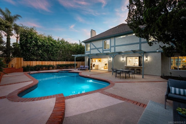 pool at dusk with a pergola and a patio