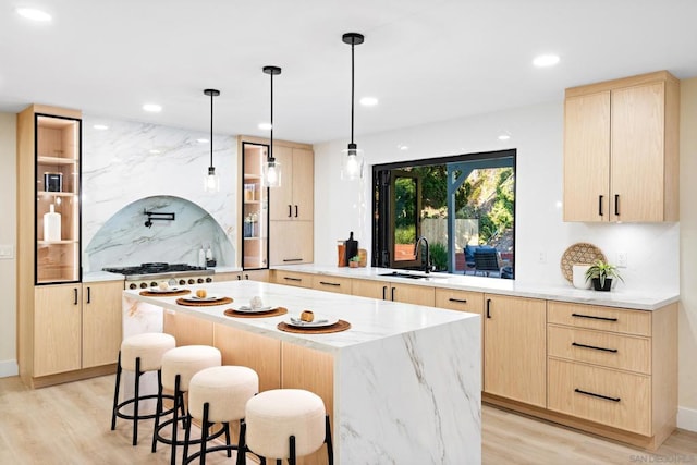 kitchen with sink, a center island, light brown cabinetry, and hanging light fixtures