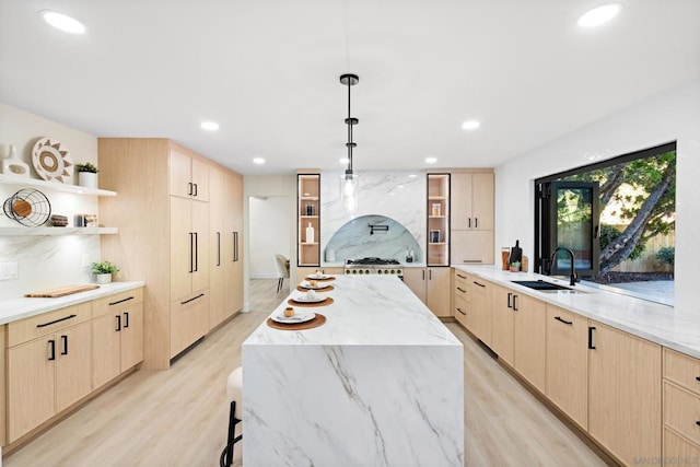 kitchen featuring a center island, light brown cabinetry, light wood-type flooring, and hanging light fixtures