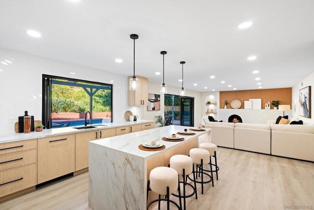 kitchen with pendant lighting, a center island, light hardwood / wood-style floors, a kitchen bar, and sink