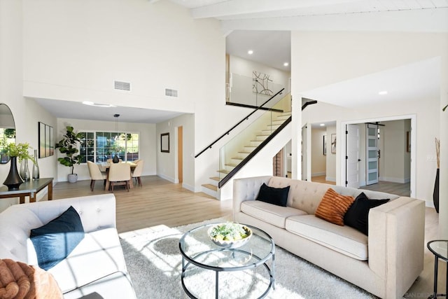 living room featuring high vaulted ceiling, light hardwood / wood-style flooring, and beam ceiling