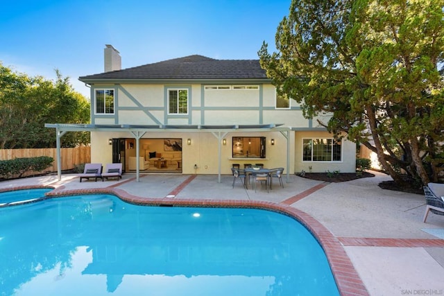 rear view of house with a swimming pool with hot tub and a patio area