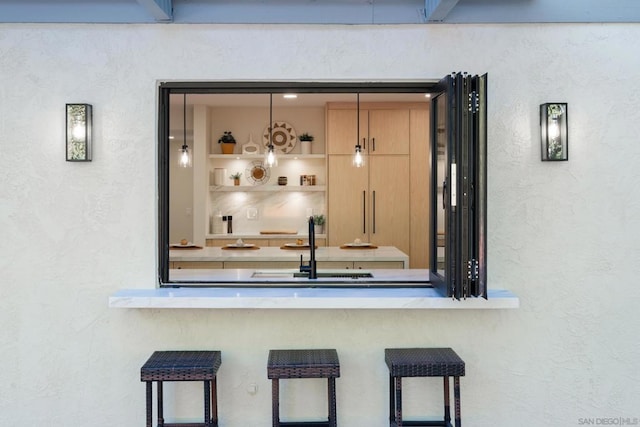 bar with sink and light brown cabinets