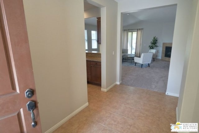 corridor with lofted ceiling and light tile patterned floors