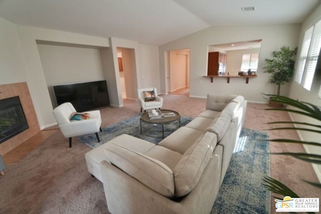 living room with carpet flooring, a tiled fireplace, a wealth of natural light, and lofted ceiling