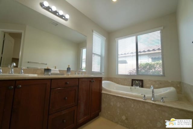 bathroom with tile patterned floors, vanity, and a relaxing tiled tub