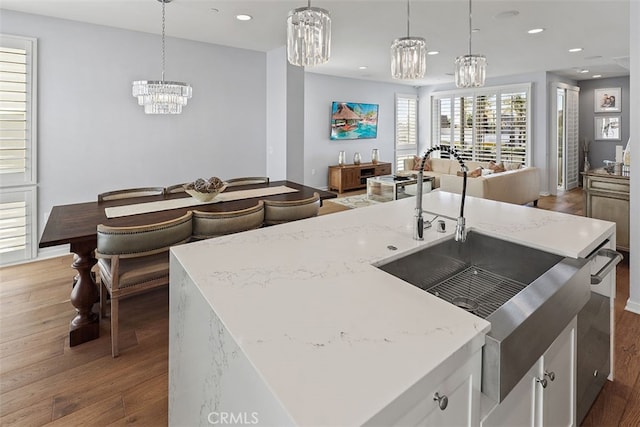 kitchen featuring an island with sink, dark wood-type flooring, white cabinets, and hanging light fixtures