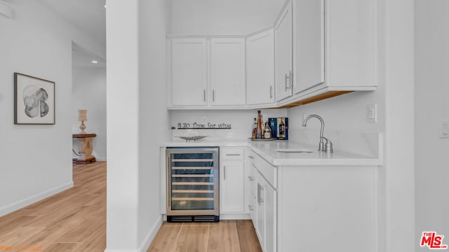 bar featuring wine cooler, white cabinetry, light hardwood / wood-style floors, and sink