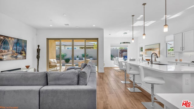 living room featuring plenty of natural light, sink, and light hardwood / wood-style flooring