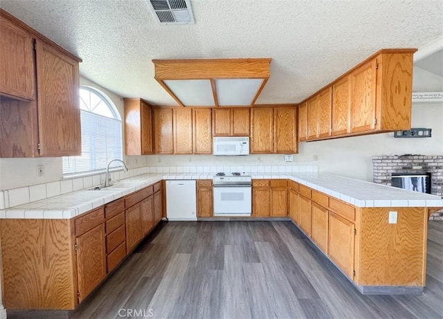 kitchen featuring kitchen peninsula, a textured ceiling, white appliances, dark wood-type flooring, and sink