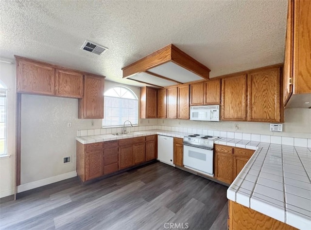 kitchen featuring tile countertops, white appliances, dark wood-type flooring, sink, and a textured ceiling