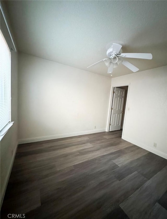 empty room with ceiling fan, dark hardwood / wood-style flooring, and a textured ceiling