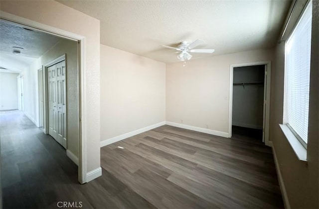 unfurnished bedroom featuring multiple windows, a textured ceiling, dark hardwood / wood-style flooring, and ceiling fan