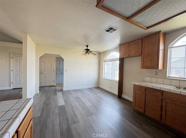 kitchen with a textured ceiling, dark hardwood / wood-style floors, tile counters, and ceiling fan