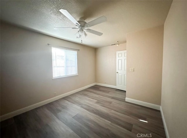 empty room with ceiling fan, dark hardwood / wood-style flooring, and a textured ceiling