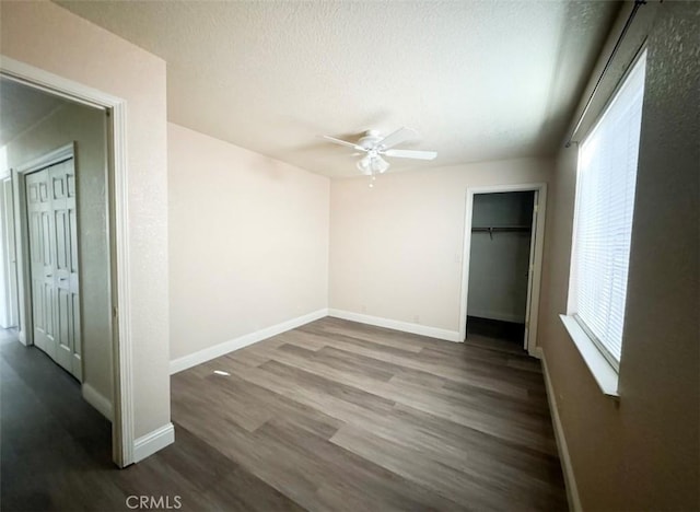 unfurnished bedroom with ceiling fan, dark hardwood / wood-style flooring, and a textured ceiling