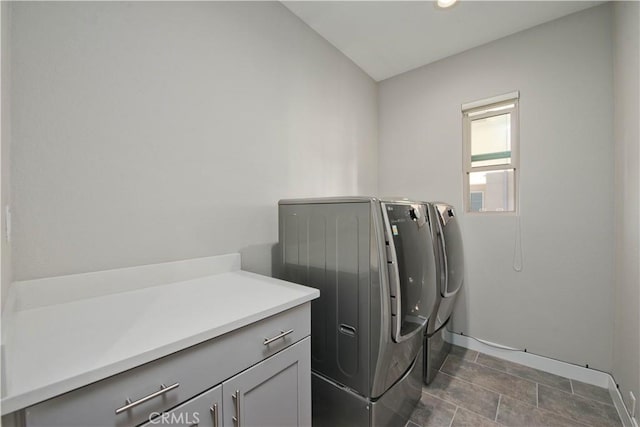 clothes washing area with washer and clothes dryer and cabinets