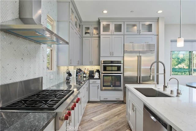 kitchen featuring pendant lighting, stainless steel appliances, plenty of natural light, and wall chimney exhaust hood