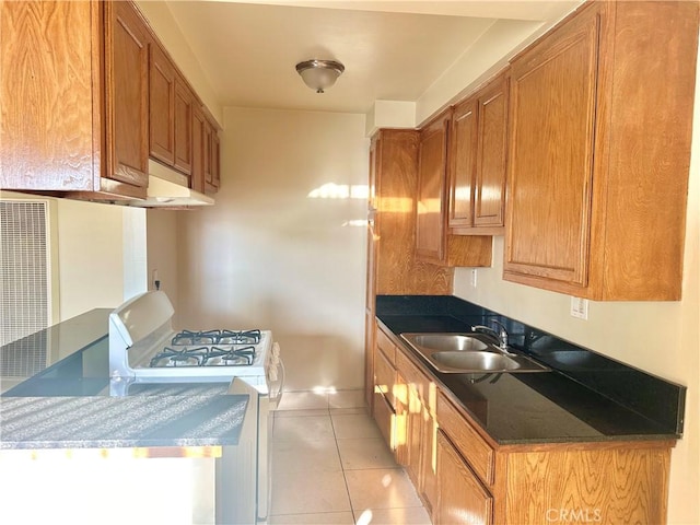 kitchen with white gas range, sink, and light tile patterned floors