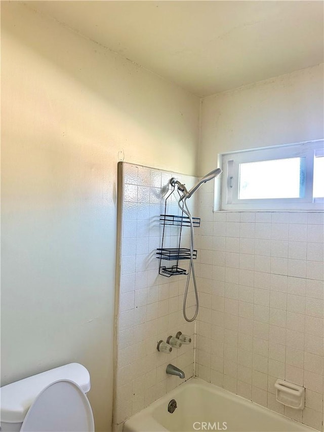 bathroom featuring toilet and tiled shower / bath