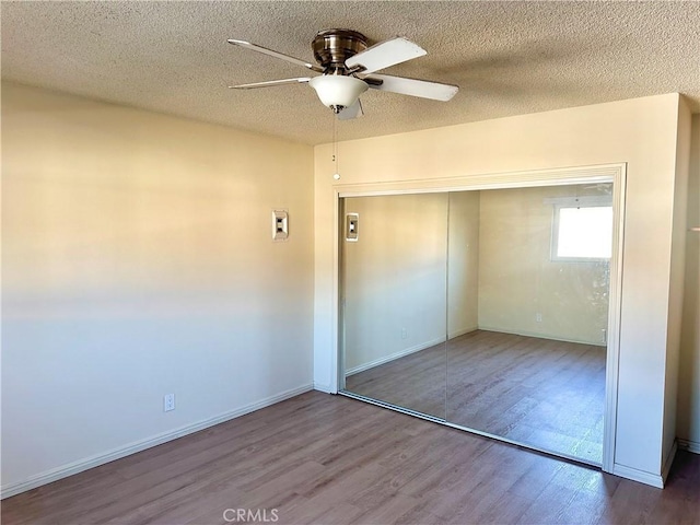 unfurnished bedroom with ceiling fan, a closet, light hardwood / wood-style floors, and a textured ceiling