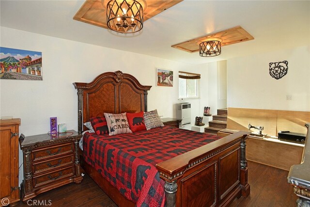 bedroom with heating unit, dark hardwood / wood-style flooring, and an inviting chandelier