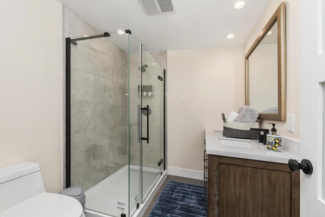 bathroom with hardwood / wood-style floors, vanity, toilet, and a shower with shower door