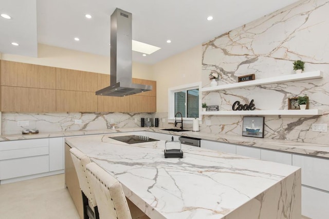 kitchen featuring decorative backsplash, a skylight, extractor fan, a center island, and white cabinetry