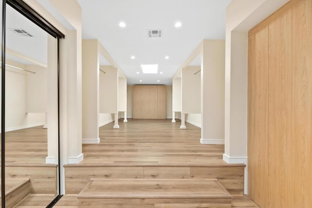 hall with light hardwood / wood-style floors and a skylight