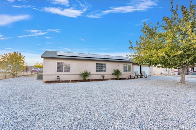 rear view of property with solar panels, central AC, and a garage