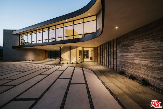 back house at dusk featuring a patio