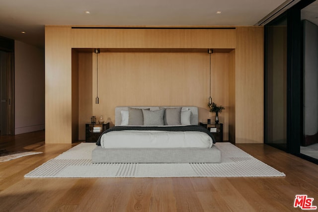 bedroom with wood walls and light hardwood / wood-style flooring