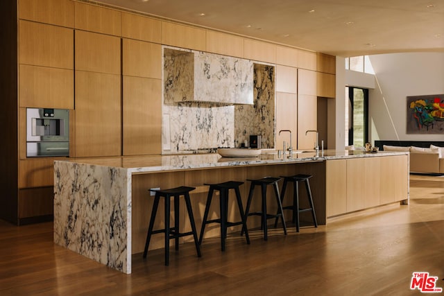 kitchen featuring a kitchen bar, light stone counters, and dark wood-type flooring