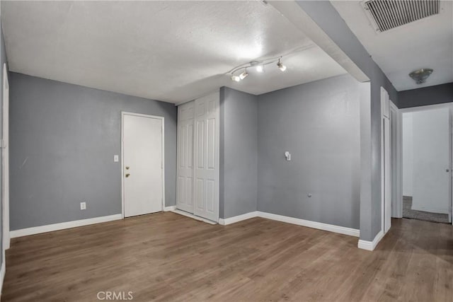 interior space with baseboards, wood finished floors, visible vents, and a textured ceiling