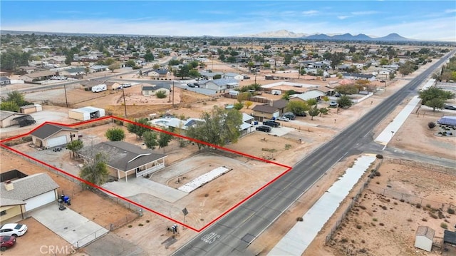 drone / aerial view featuring a residential view, a mountain view, and a desert view