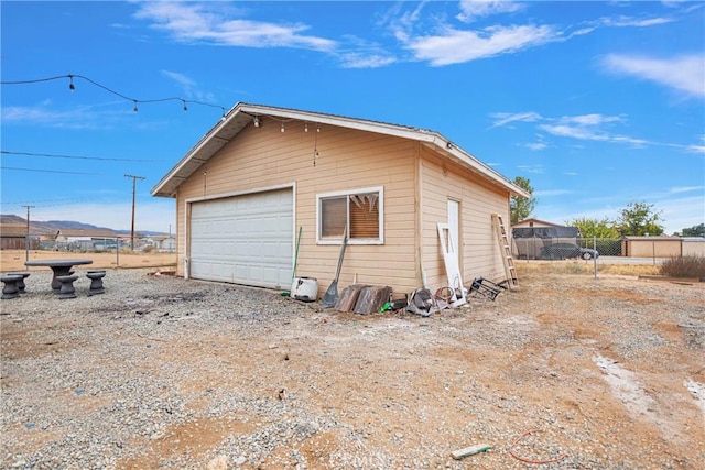 view of side of property with an outdoor structure, fence, and a detached garage