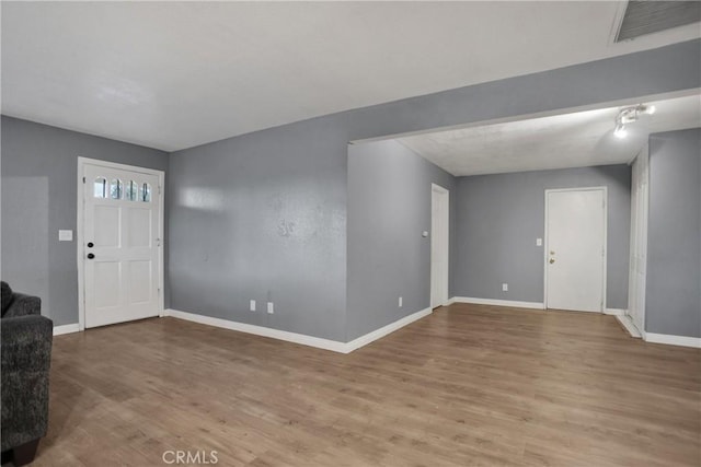 foyer with wood finished floors, visible vents, and baseboards
