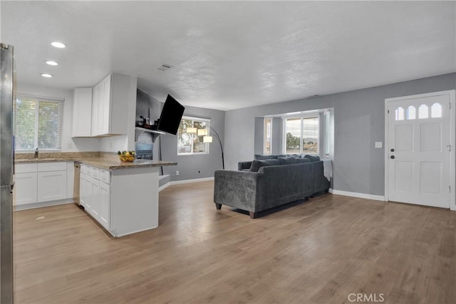 unfurnished living room featuring recessed lighting, visible vents, light wood-style flooring, and baseboards