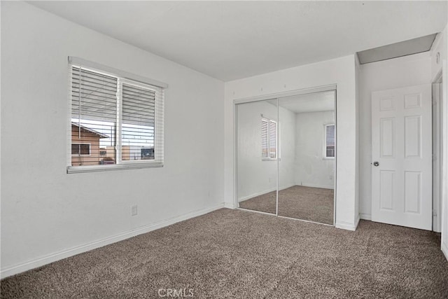 unfurnished bedroom featuring multiple windows, a closet, carpet, and baseboards