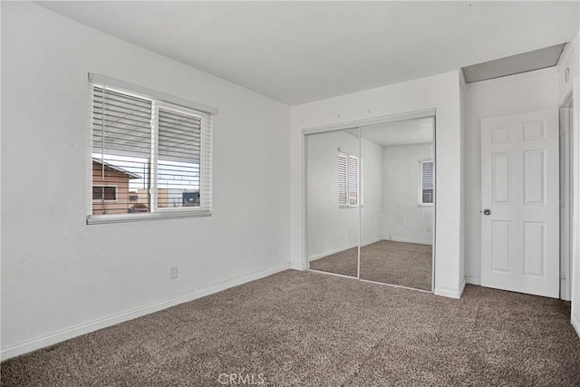 unfurnished bedroom with baseboards, carpet, a closet, and multiple windows
