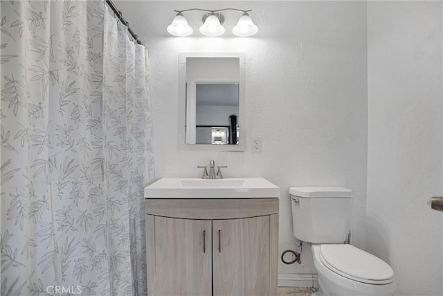 bathroom with toilet, a textured wall, and vanity