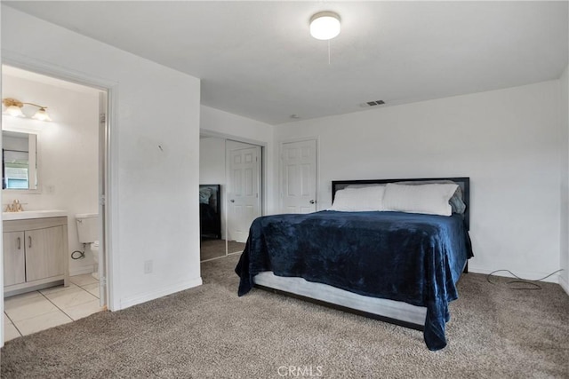 bedroom featuring light tile patterned flooring, connected bathroom, light colored carpet, visible vents, and a closet